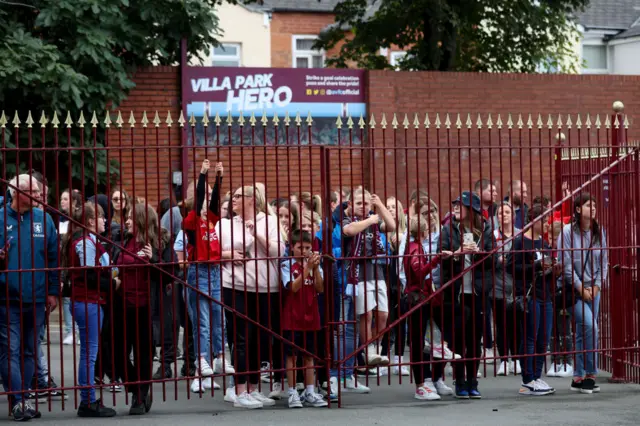 Villa fans stand outside the gates where the bus enters the ground.