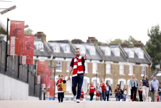 A father holds hands as he walks with his daughter outside the ground.