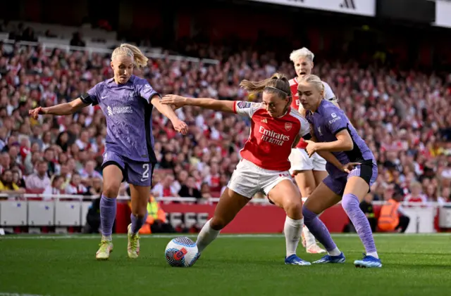 McCabe is challenged by several Liverpool defenders.