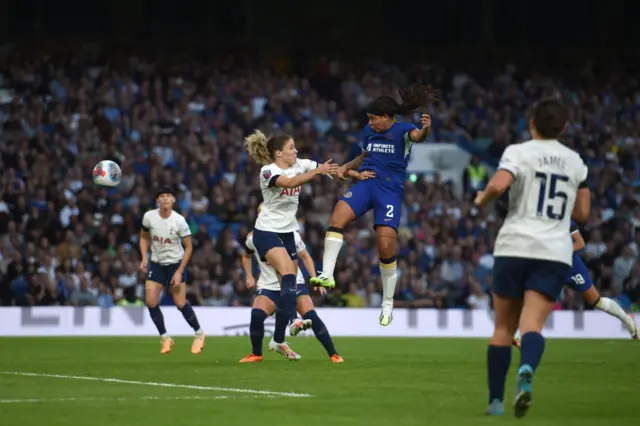 Fishel leaps into the air to head the ball towards goal.