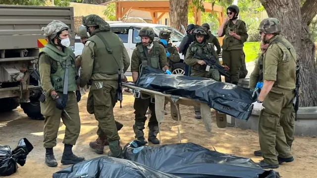 Israeli soldiers move bodies in Kfar Aza kibbutz