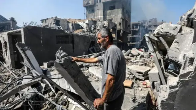 A resident of Gaza City's Rimal neighbourhood inspects the damage after a night of Israeli air strikes (10 October 2023)