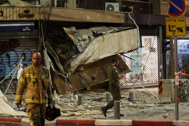 A rescuer walks in front of a damaged shop in Tel Aviv, which was hit by a rocket fired by Hamas militants on October 7, 2023