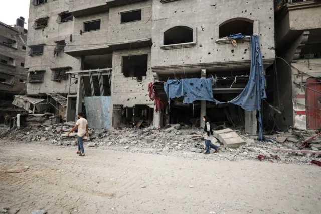 Palestinians walks infront of the rubble of destroyed buildings after an Israeli air strikes in Gaza City, on October 9, 2023