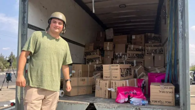 Alon standing next to a lorry filled with boxes of supplies