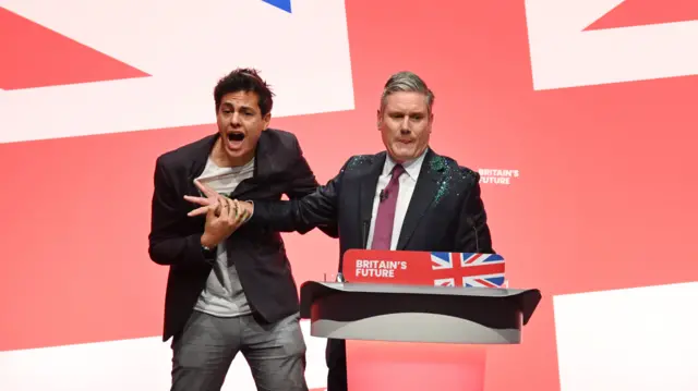 Labour Party Conference - a protester throws glitter over Sir Keir Starmer as he is about to start his speech, 10 October 2023.