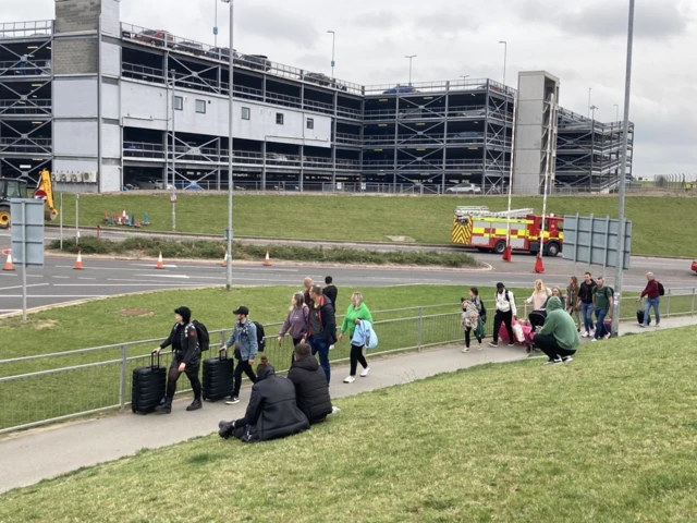 Passengers walking past a car park to get to the airport terminal