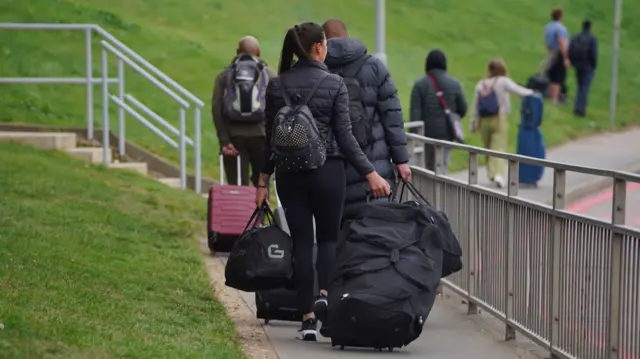 The backs of passengers at Luton Airport