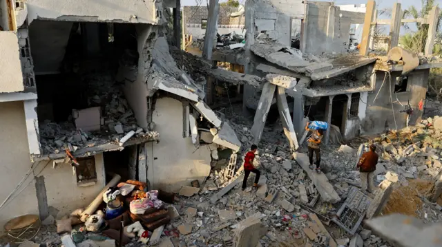 Palestinians carry belongings near their damaged house following Israeli strikes, in Khan Younis in the southern Gaza Strip October 11, 2023