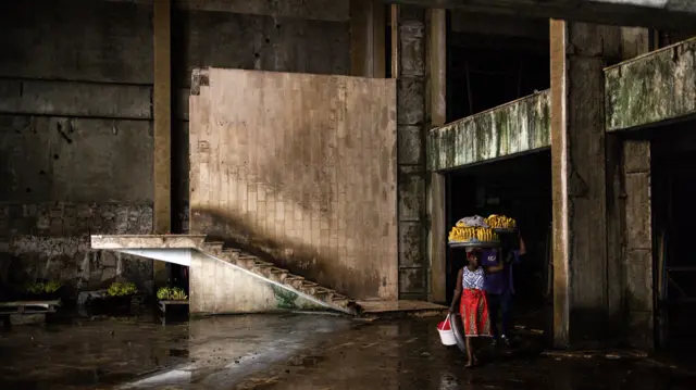 Liberian banana vendors carry their fruit through the derelict E.J. Roye skyscraper in the capital city, Monrovia.