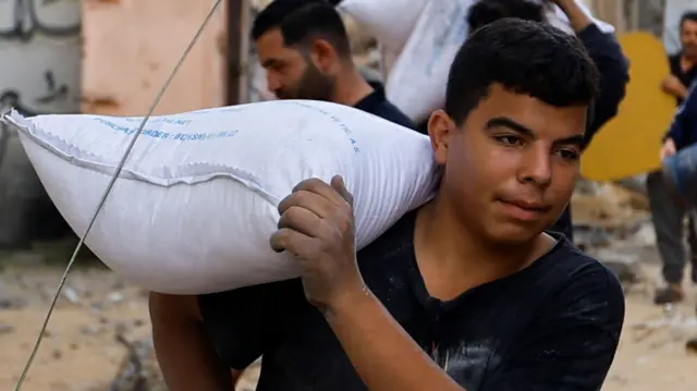 A Palestinian carries a sack of flour retrieved from a house hit by Israeli strikes, in Khan Younis in the southern Gaza Strip October 11, 2023.