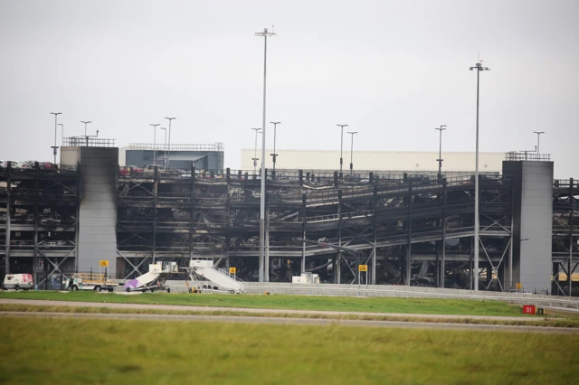 Wide shot showing side of car park. There is black smoke damage and you can see a partial collapse.