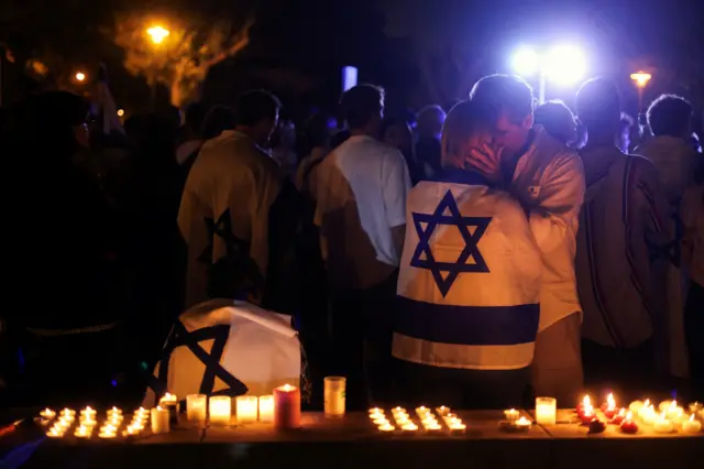 People stood embracing by candlelight