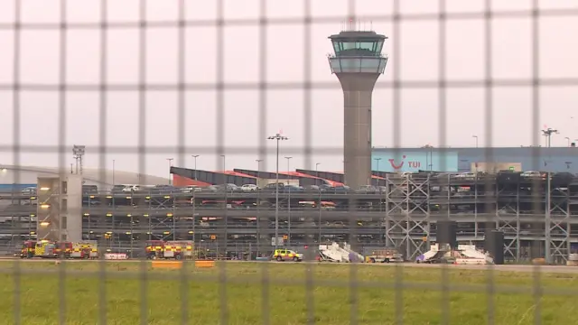 Through a wire gate you can see emergency services still at the scene