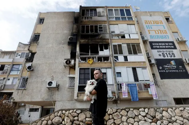 A man stands outside a building damaged by rockets fired from Gaza