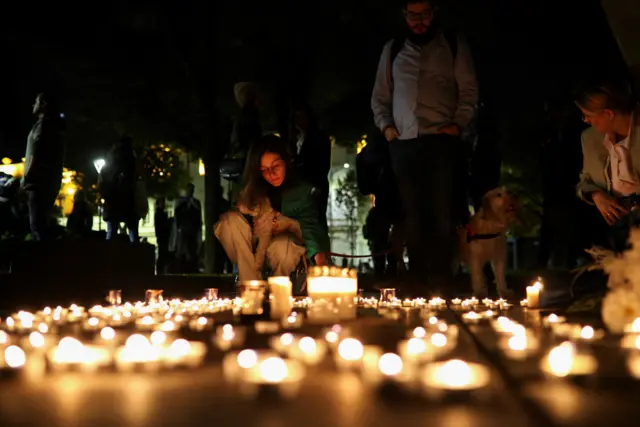 People lighting candles on the floor