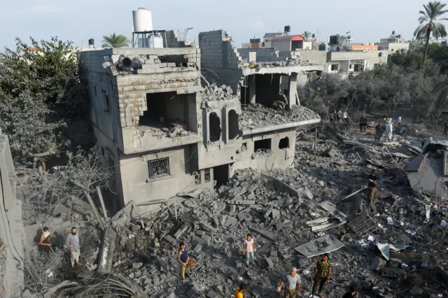 Palestinians gather on rubble near damaged buildings in the aftermath of Israeli strikes, in Khan Younis in the southern Gaza Strip October 11, 2023. REUTERS/Ibraheem Abu Mustafa