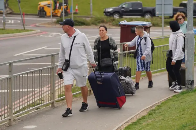 Passengers with suitcases walk away from the airport