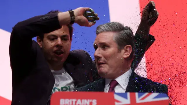 A protester drops glitter on Sir Keir Starmer