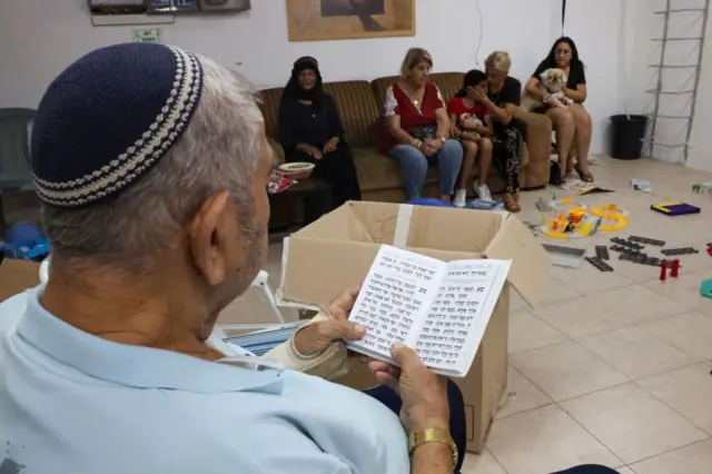 An Israeli man reads from the Torah as people take shelter during a rocket attack