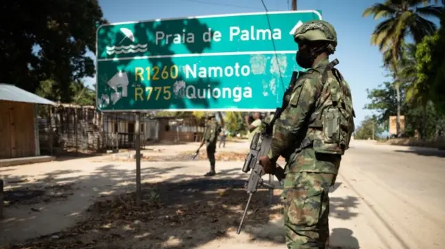 A Rwandan soldier walks in front of a burned truck near Palma, Cabo Delgado, Mozambique on September 22, 2021. - Since July 2021 a contingent of a thousand Rwandan soldiers and policemen is deployed to Mozambique to fight insurgents that were terrorising populations.