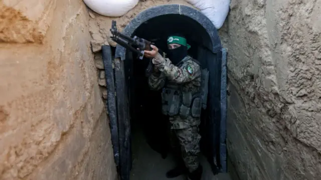 A fighter from Izz al-Din al-Qassam stands in front of a tunnel during an exhibition of weapons, missiles and heavy equipment for the military wing of Hamas in the Maghazi camp in the central Gaza Strip, during the commemoration of the 2014 war that lasted 51 days between Gaza and Israel.