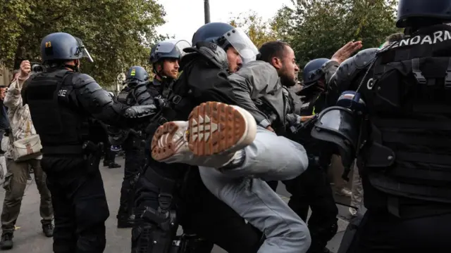 A riot policeman in Paris grabs a demonstrator who wanted to pass the police cordon during banned demonstration in support of the Palestinian people