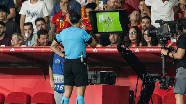 The referee checks the incident on the monitor