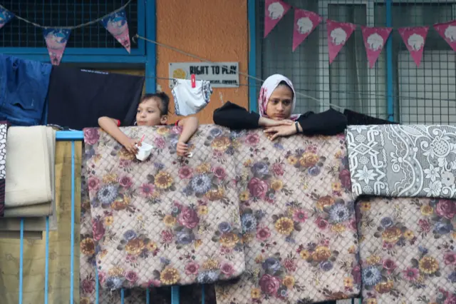 Two displaced Palestinian citizens lean on a wall