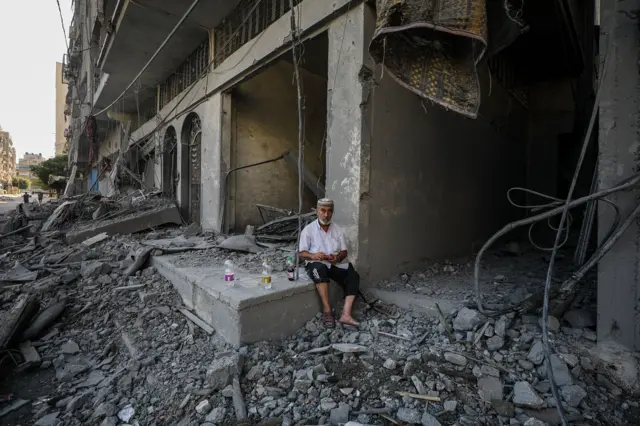 A Palestinian man sits among the rubble following an Israeli air strike in the north of Gaza City