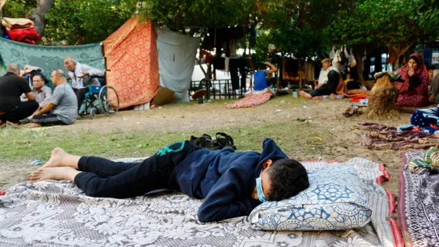 A boy rests as Palestinians who fled their homes due to Israeli strikes shelter at al-Shifa hospital in Gaza City