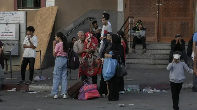 A group of people stand with their belongings on the street in Gaza City