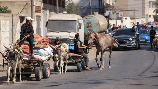 Palestinians with their belongings flee to safer areas in Gaza City after Israeli air strikes, on October 13, 2023.