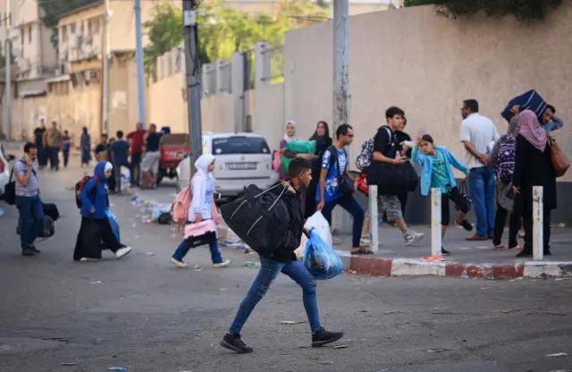 Palestinians carrying their belongings flee to safer areas in Gaza City after Israeli air strikes