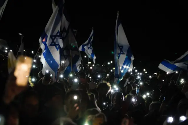 People wave Israeli flags during a vigil in solidarity with Israel, in Montevideo, Uruguay