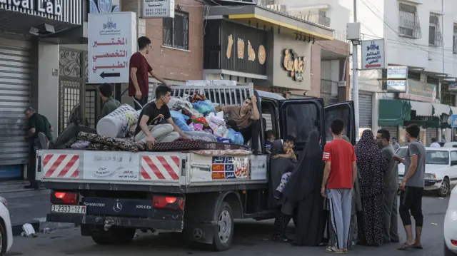 Residents of Gaza city and their belongings are pilled onto a pick-up truck as they begin to evacuate the northern part of the territory