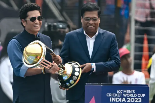 Sachin Tendulkar (L), India's former cricket player and International Cricket Council (ICC) global ambassador for men's cricket World Cup 2023, carries the World Cup trophy before the start of the 2023 ICC Men's Cricket World Cup one-day international (ODI) match between India and Pakistan at the Narendra Modi Stadium in Ahmedabad