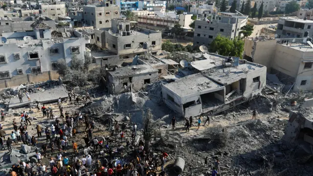 Palestinians gather around the rubble in the aftermath of Israeli strikes in Khan Younis