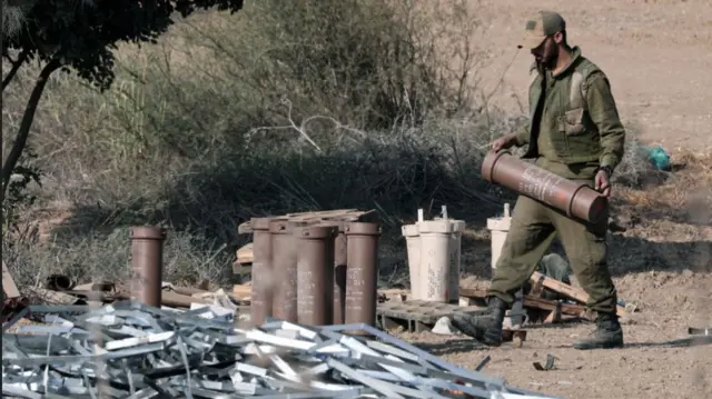 An Israeli soldier recovers a spent shell casing following an artillery strike against the Gaza Strip from Sderot in southern Israel