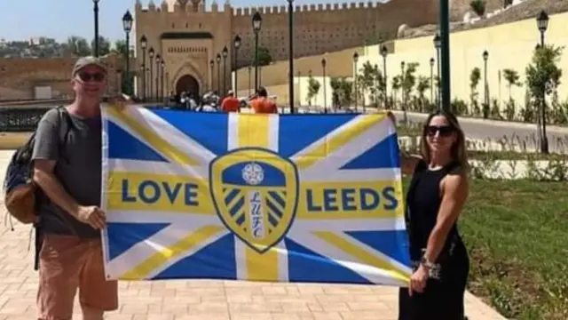 David Barr and his sister-in-law Naomi Shitrit hold up a Leeds United FC flag