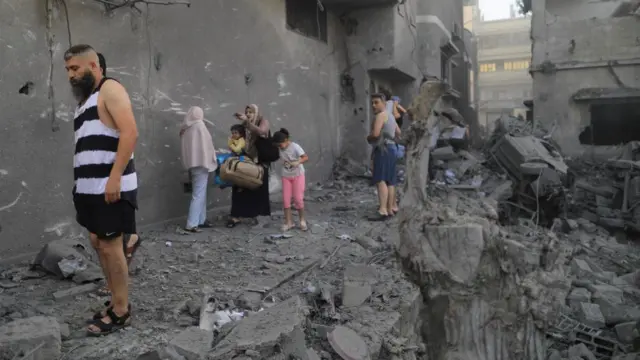 Palestinians walk at the site of Israeli strikes, in Khan Younis in the southern Gaza Strip