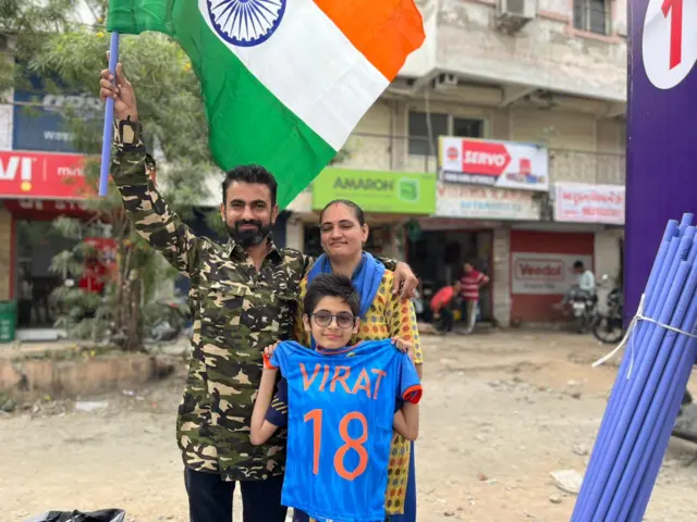 Dhananjay K with his parents, holding a Kohli jersey