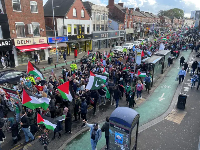 Protestors make their way through the Rusholme area of south Manchester