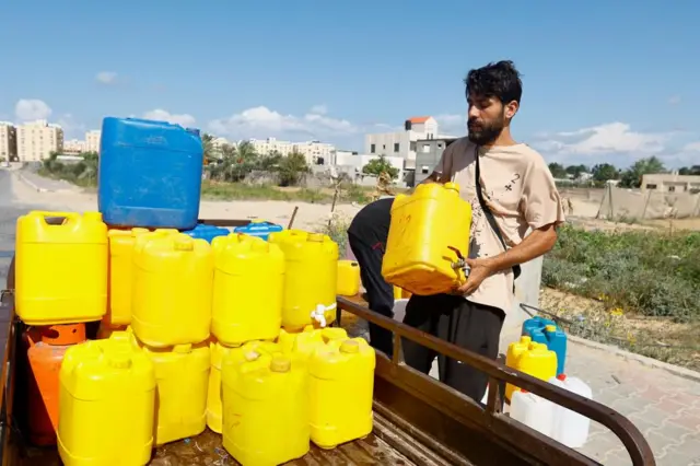 A man loads cannisters of water onto a truck in Khan Younis