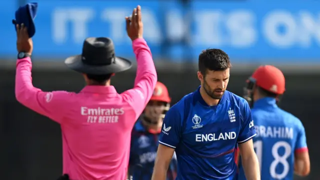 Mark Wood looks dejected as the umpire signals a six