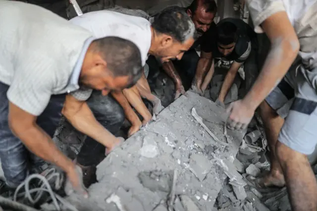 People searching for survivors lifting rubble from a building destroyed in an Israeli air strike