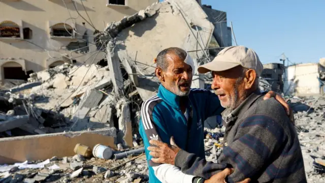 Palestinian man stands near the rubble of his destroyed home