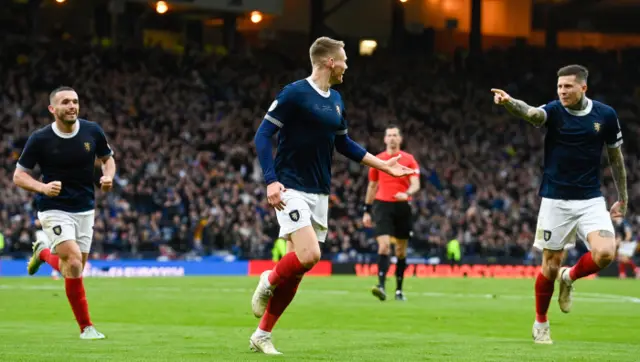 Scott McTominay rushes away in celebration with Lyndon Dykes and John McGinn