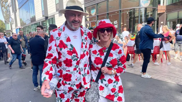 Trevor and Jean in a suit and dress covered in red roses