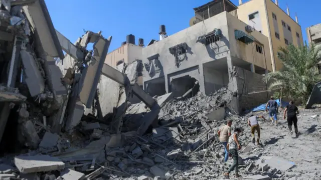 Palestinians run past the rubble following Israeli strikes in Gaza City on 15 October